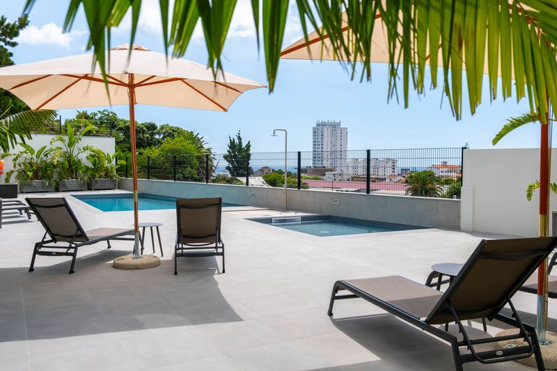 Terraço com piscina, espreguiçadeiras e vista sobre a cidade de Ponta Delgada